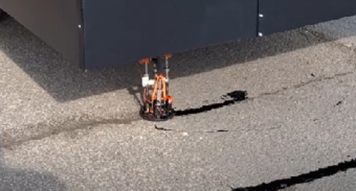 포트홀 방지 로봇이 차체 하단에서 막대기형 장비를 내려 도로의 균열을 메우고 있다. 이 로봇은 이달 초 영국 남부 허트퍼드셔주에서 시험 가동에 성공했다. 허트퍼드셔주 지방정부 제공