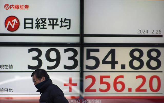 한 일본 시민이 지난달 26일 도쿄 시내에서 일본 닛케이225 평균주가(닛케이지수)가 적혀 있는 증시 현황판 앞을 지나가고 있다. 도쿄=AFP 연합뉴스