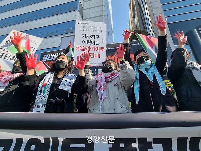 팔레스타인과 연대하는 한국시민사회 긴급행동에 속한 활동가들이 18일 서울 중구 동대입구역 앞에서 팔레스타인 희생자들의 피를 상징하는 ‘빨간 손’을 들어보이고 있다. 전지현 기자