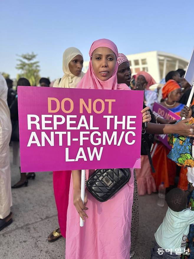 시민단체 ‘세이프 핸즈 포 걸스’ 설립자 자하 두쿠레가 18일(현지시각) 감비아 세레쿤다 의회 밖에서 FGM(여성성기훼손) 금지법 폐기에 반대하는 피켓을 들고 시위하고 있다. 어린 시절 할례 시술을 당한 후 시민단체를 설립한 두쿠레는 지난 2015년 통과한 여성 할례 금지법을 감비아 의회가 폐지하려는 움직임을 보이자 이에 항의하고 나섰다. 2024.03.19. [세레쿤다=AP/뉴시스]