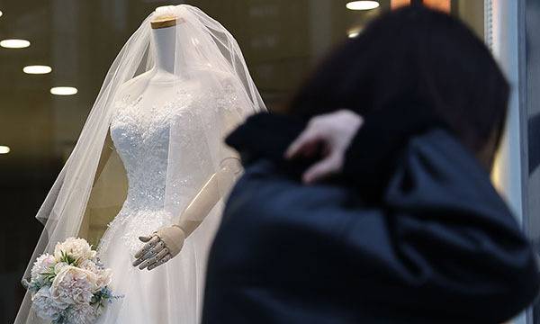 19일 서울 마포구 아현동 웨딩거리에서 한 시민이 웨딩드레스 앞을 지나고 있다. 연합뉴스