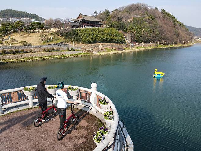 에코레일에서 빌려주는 미니 전기자전거를 타고 밀양교에서 영남루를 바라보는 사람들. 영남루는 지난해 12월 국보로 승격됐다.