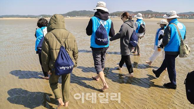태안 신두리 해수욕장에서 맨발로 땅을 밟으며 걷는 ‘어씽’ 체험을 하는 여행객들