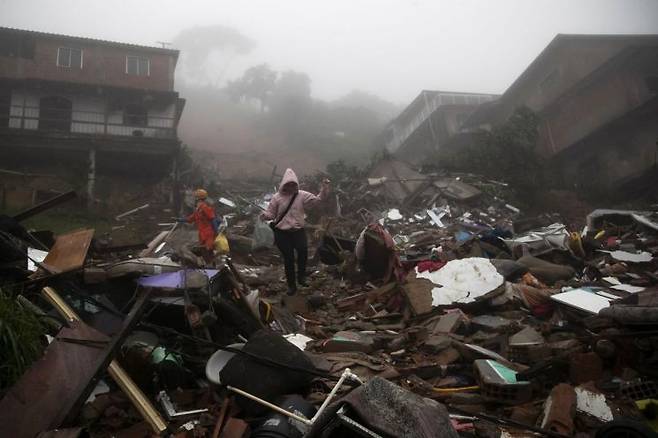 23일(현지시간) 브라질 리우데자네이루주 페트로폴리스에서 주민이 폭우와 산사태로 엉망이 된 마을을 조심스럽게 걷고 있는 모습 [이미지출처=AP연합뉴스]