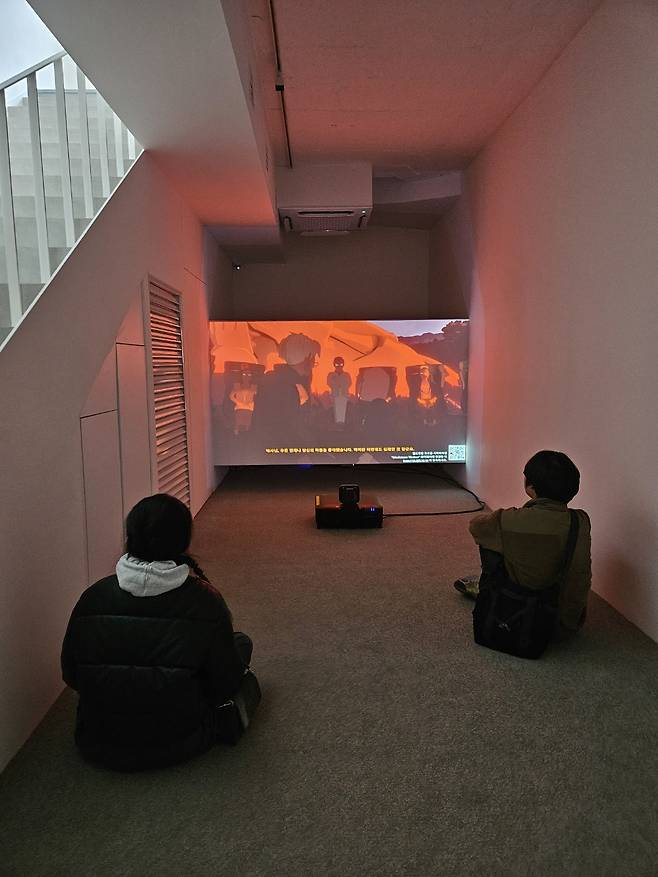 Visitors watch “Life After BOB: The Chalice Study Experience (LABX)" at Gladstone Gallery in Seoul, March 5, interacting with the AI-based anime using their smartphones. (Park Yuna/The Korea Herald)