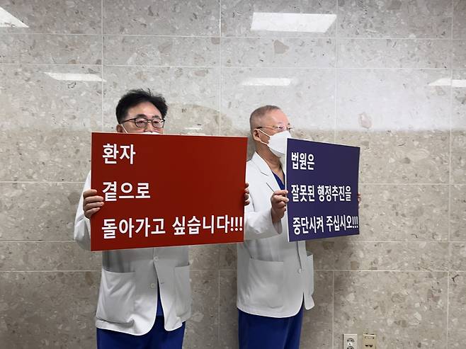 Medical professors at Yonsei University hold signs that read, “(We) want to return to patients (left)” and that the “court should stop carrying out improper administration initiatives” in protest against the government’s expansion plan, Monday. (Park Jun-hee/The Korea Herald)