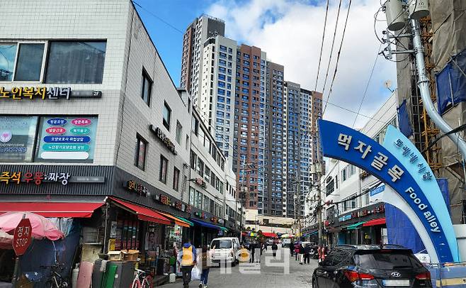 지난 26일 서울 서대문구 남가좌동 모래내시장 먹자골목에서 오래된 점포 거리 너머로 가재울 뉴타운 신축 아파트 단지가 보이고 있다.(사진=김범준 기자)