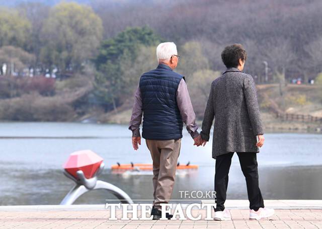 봄 나들이를 나선 중년 부부가 다정히 손을 잡은 채 산책하고 있다.