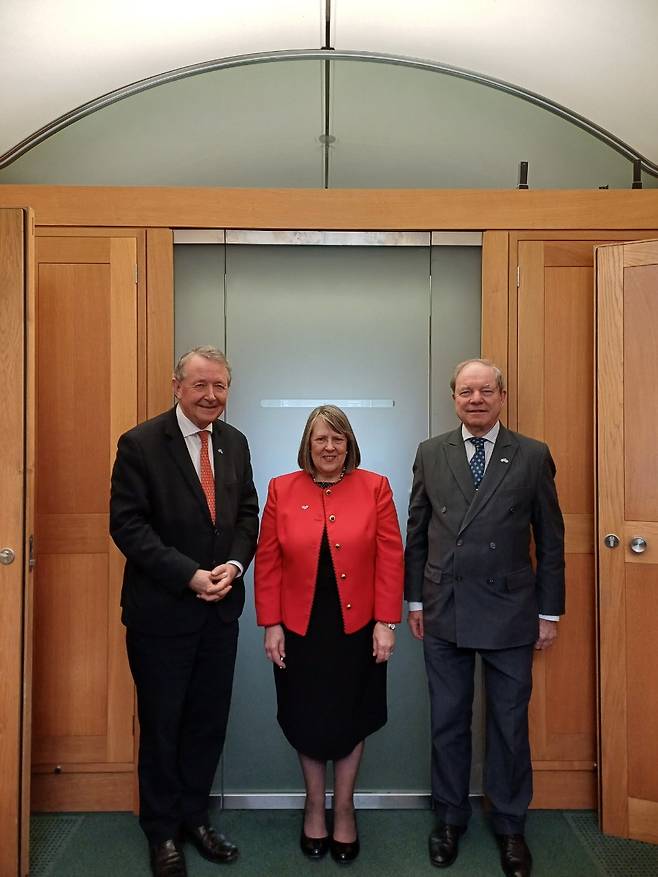 From left: Member of the House of Lords David Alton, Member of Parliament Fiona Bruce and Member of Parliament Geoffrey Clifton-Brown don forget-me-not badges during an event at the Palace of Westminster in London on Tuesday. (Unification Ministry)