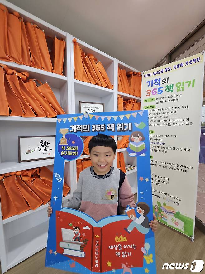 지난해 기적의 365책 읽기 독서 운동에 참여한 어린이가 홍보물 앞에서 사진을 찍고 있다.(금산군 제공)/ 뉴스1