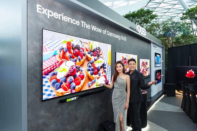 삼성전자가 싱가포르 공항 '주얼 창이'에서 TV 신제품 체험존을 열었다고 29일 밝혔다. 삼성전자 직원과 모델이 신제품을 소개하고 있다.  삼성전자