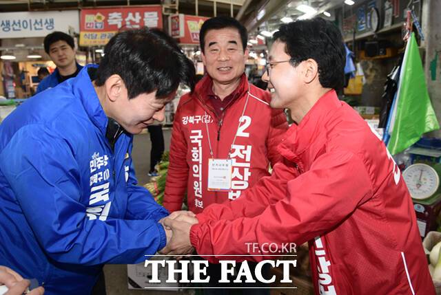 한민수 더불어민주당 강북을 후보(왼쪽)와 전상범 국민의힘 강북갑 후보가 2일 오전 서울 강북구 수유시장에서 유세 도중 만나 악수하고 있다.