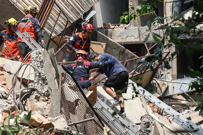 3일(현지 시각) 대만 동부를 강타한 규모 7.4의 강진으로 파손된 건물에서 구조된 생존자를 구급대원들이 돕고 있다. ⓒ AFP=연합뉴스