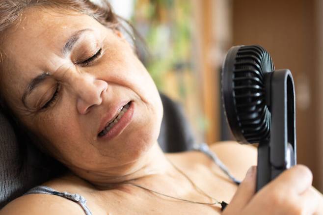 나이든 여성이 무더위를 참지 못해 '손풍기'(휴대용 선풍기)로 땀을 말리고 있다. 하지만 땀 배출 능력이 뚝 떨어진 노인에겐 선풍기의 냉각 효과가 거의 없다는 연구 결과가 나왔다. [사진= 게티이미지뱅크]