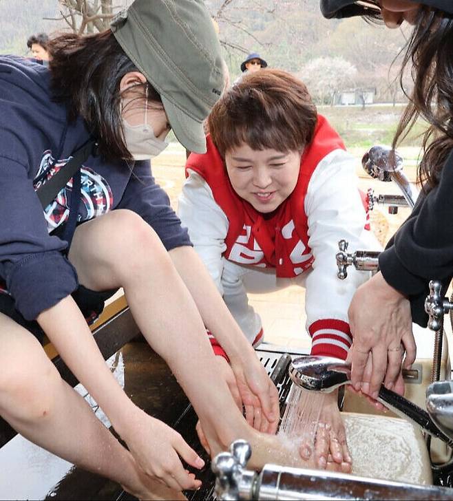 국민의힘 김은혜 후보(경기 성남분당을)가 성남 구미동 황톳길에서 시민들의 발을 씻어주고 있다. 김 후보 캠프 제공