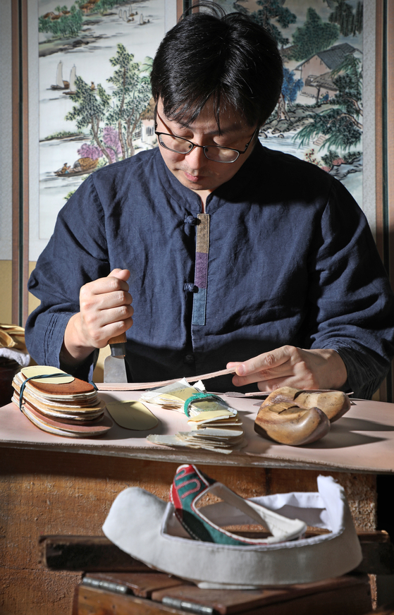Hwang cuts out baekbi, a lining attached to the outer rims, to make a traditional shoe.  [PARK SANG-MOON]
