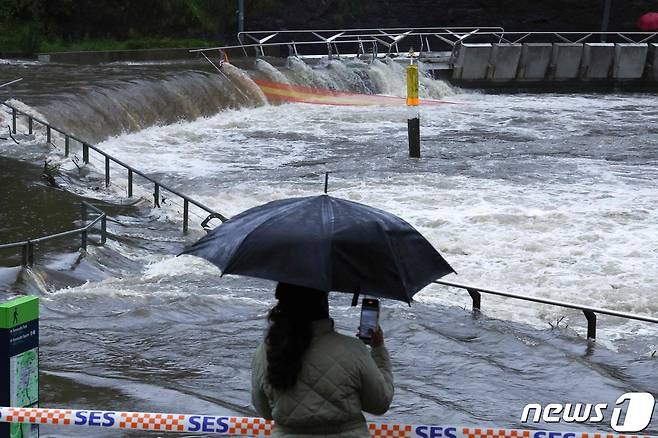 한 여성이 5일 시드니 페리선창에서 넘쳐 흐르는 패러메타 강물을 발보고 있다. 호주 동부지역에 폭우가 집중되며 태평양 연안에 홍수, 비상 경고가 되풀이 되고있다. 2024.04.05 ⓒ AFP=뉴스1 ⓒ News1 김성식기자