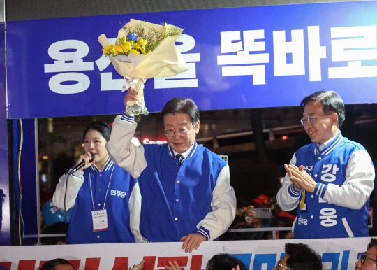 더불어민주당 이재명 대표가 9일 용산역 앞 광장에서 열린 '정권 심판, 국민승리 총력 유세'에서 지지자가 선물한 꽃다발을 들어 보이고 있다.  연합뉴스