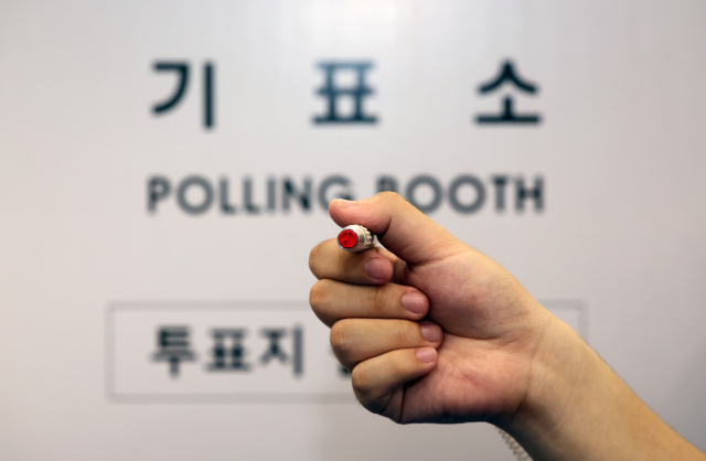 제22대 국회의원 선거를 하루 앞둔 9일 오후 서울 영등포구 YDP미래평생학습관에 마련된 투표소에서 관계자가 기표 용구를 들어 보이고 있다. 연합뉴스