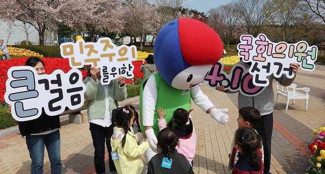 제22대 국회의원 선거를 하루 앞둔 9일 오후 울산시 남구 울산대공원 남문광장 튤립정원에서 울산시선관위 관계자들이 투표 독려 캠페인을 벌인 가운데 어린이들이 선관위 캐릭터 ‘바루’ 주변에 모여들어 있다. [연합]