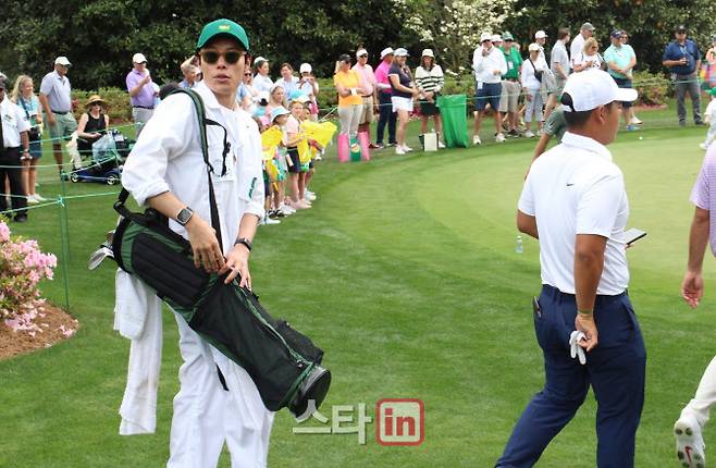 배우 류준열(왼쪽)이 마스터스의 상징인 하얀색 캐디 수트에 골프백을 메고 파3 콘테스트가 열리는 코스로 이동하고 있다. (사진=주영로 기자)