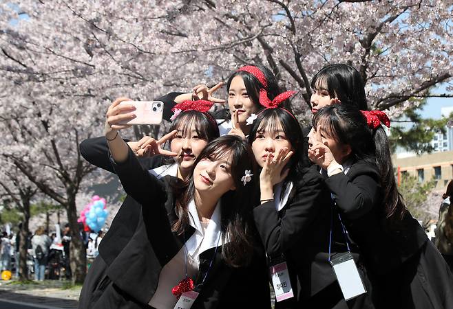 만우절인 4월 1일 부산 남구 국립부경대학교에서 대학생들이 옛 교복을 입고 벚꽃을 배경으로 기념사진을 찍고 있다./김동환 기자