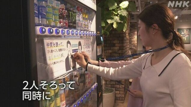 일본의 한 회사 직원들이 자동 음료 판매기 앞에서 사원증을 찍고 있는 모습. /NHK