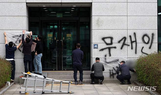 [서울=뉴시스] 김명년 기자 = 11일 오후 서울 서초동 서울고등검찰청 건물에 문재인 전 대통령과 서훈 전 국가정보원장을 비방하는 내용의 낙서를 하고 건물 창문에 돌을 던진 40대 남성이 경찰에 붙잡혔다. 사건 현장에서 청사 관계자들이 비닐막으로 낙서를 가리고 있다. 2024.04.11. kmn@newsis.com