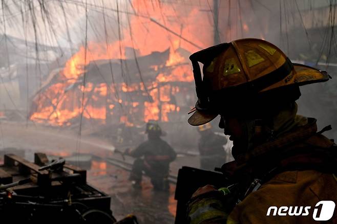 지난 달(현지시간) 필리핀 케손시티의 비공식 정착촌에서 난 불을 소방관들이 진압하는 모습. ⓒ AFP=뉴스1 ⓒ News1 정지윤 기자