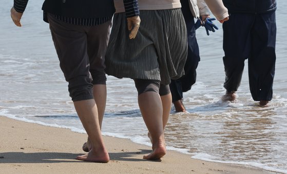 지난 14일 부산 송정해수욕장을 방문한 시민이 맨발로 바닷가를 걷고 있다. 송봉근 기자