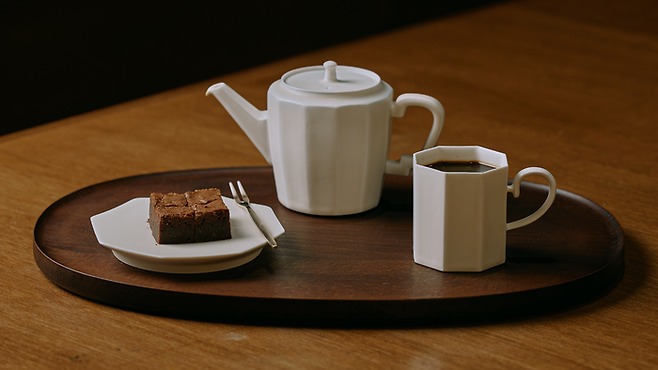 스페셜티 커피 브랜드 포멜로빈이 세라믹 스튜디오 소만과 함께 선보인 백자 주전자와 컵, 접시에 커피와 디저트가 담겨 있다. 포멜로빈은 이번 아트 오앤오에서 카페 라운지를 운영한다. 포멜로빈