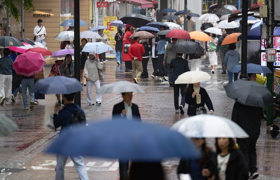 전국 대부분 지역에 비가 내린 15일 오후 서울 중구 명동거리에서 외국인 관광객들이 발걸음을 재촉하고 있다. 뉴스1