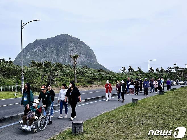 제주관광공사가 19일 제주올레 10코스 휠체어 구간에서 진행한 '무장애 올레길 걷기' 참가자들이 올레길을 걷고 있다.(제주관광공사 제공)/뉴스1