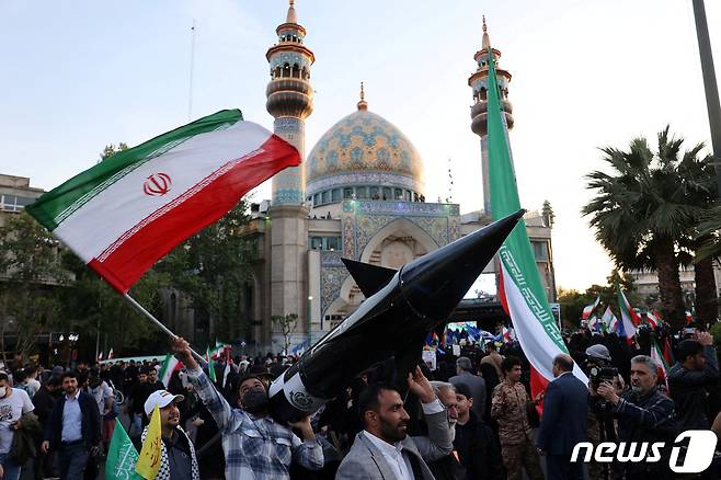 이스라엘이 이란의 공습을 받은 다음 날인 15일(현지시간) 이란 수도 테헤란에서 이란인들이 미사일 모형을 들고 자축하고 있다. 2024.04.15 ⓒ 로이터=뉴스1 ⓒ News1 정지윤 기자