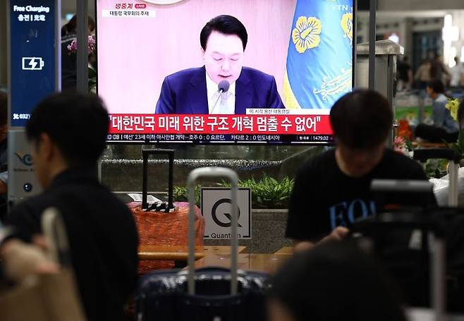 지난 16일 오전 인천국제공항 제1여객터미널 입국장에서 공항 이용객들이 TV로 중계되는 윤석열 대통령의 국무회의 발언을 지켜보고 있다.ⓒ 연합뉴스