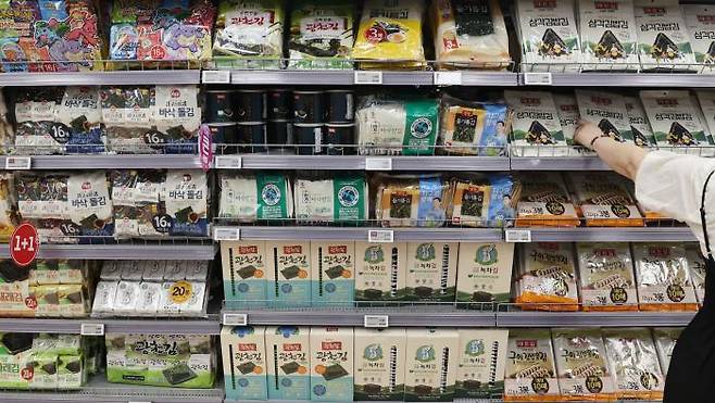 A shopper selects seaweed on display at a hypermarket in Seoul on Aug. 18. Three mid-sized companies in the top five in the seasoned seaweed market, including Gwangcheon Seaweed, Bible Food and Daecheon Seaweed, have been raising prices this month. Yonhap News Agency