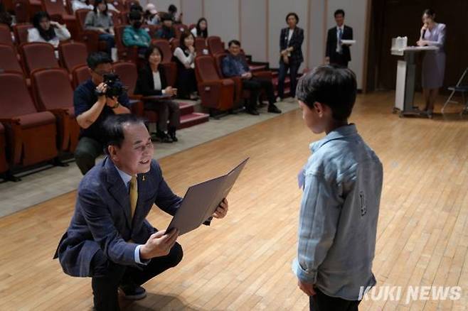 김지철 교육감이 2024 행복나눔기자단으로 위촉된 학생에게 눈높이에 맞춰 무릎을 굽히며 위촉장을 수여하고 있다.