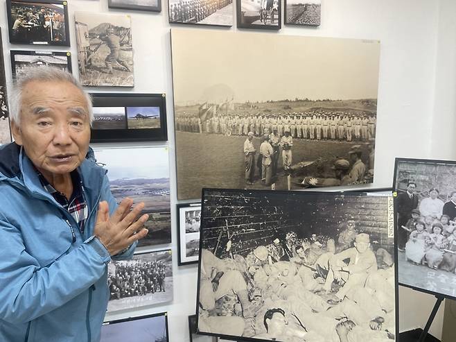 김웅철 향토사학자가 자신의 전시관에서 한국전쟁 당시 찍힌 사진에 대해 설명하고 있다. 가장 위에 있는 사진은 제주에서 진행된 중공군 사망 포로 영결식. [송은범 기자]