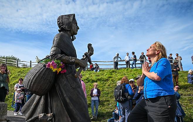 <화석을 사냥하는 여자들>의 작가 트레이시 슈발리에가 메리 에닝의 청동 조각상 앞에서 경의를 표하고 있다. 게티이미지
