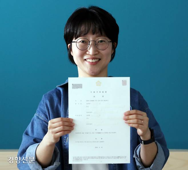 경향신문 플랫 입주자 프로젝트 ‘엄마 성 빛내기’ 참여자인 김준영씨가 수원가정법원의 심판결정문을 들고 미소 짓고 있다. 법원은 지난 22일 김씨가 청구한 성·본 변경 심판에 대해 허가를 결정했다. 서성일 선임기자 centing@kyunghyang.com