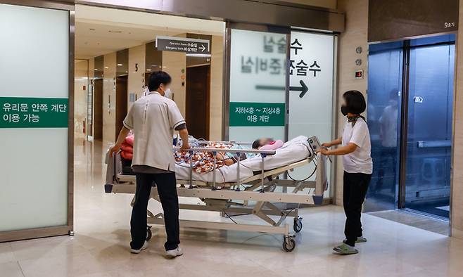 정부의 의료개혁에 반대하는 의대 교수들이 사직을 시작한 25일 서울의 한 대학병원에서 의료진이 환자와 함께 이동하고 있다. 뉴시스