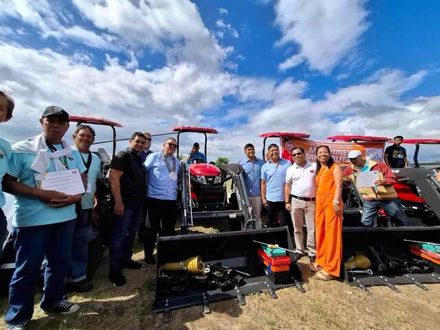 필리핀 현지에서 열린 트랙터 전달식에서 필리핀 농업부 관계자들이 트랙터 앞에서 활짝 웃고 있다. TYM