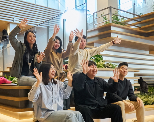LG 직원들이 새롭게 오픈한 LG트윈타워 공용공간 커넥트윈을 배경으로 단체 사진을 찍고 있다.