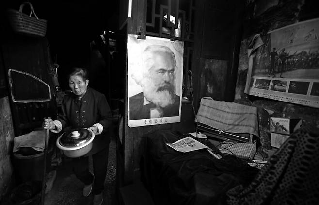이정용 기자의 출품작중 일부. 마르크스 초상화가 내걸린 집안에서 취사하러 솥을 들고 움직이는 노파의 모습을 담았다. 2016년 중국 안후이성. 스페이스22 제공