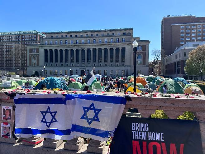 25일(현지시간) 미국 뉴욕 컬럼비아대 교정 이스라엘 국기 너머로 가자 전쟁을 반대하는 학생들이 텐트를 치고 농성을 벌이고 있다. 연합뉴스