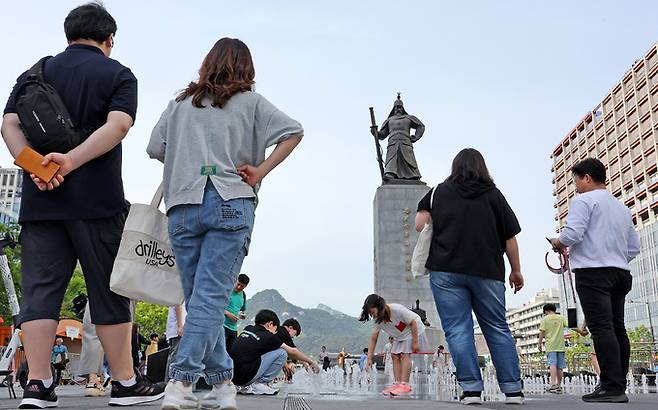 28일 오후 서울 종로구 광화문광장 이순신동상 바닥분수를 찾은 가족단위 시민들이 더위를 식히고 있다. 뉴스1