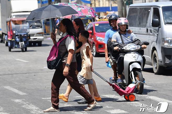 25일(현지시간) 필리핀 마닐라에서 시민들이 폭염을 피하기 위해 양산을 쓰고 걸어가고 있다. 2024.04.25/ ⓒ AFP=뉴스1 ⓒ News1 박재하 기자
