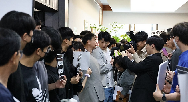 충북의대 교수·전공의·학생 등 200여명이 29일 오후 정원 규모를 결정할 것으로 알려진 교무회의가 열리는 충북대학교 대학본부 5층 대회의실 앞 복도에서 증원 반대 시위를 하고 있다. 사진은 한 교무위원이 대열 사이로 회의장에 들어가는 모습. ⓒ연합뉴스