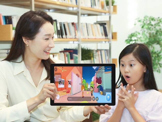 LG유플러스 모델이 한 어린이와 함께 키즈 전용 메타버스 전시관 ‘픽키즈’를 살펴보고 있다. [사진 = LG유플러스]