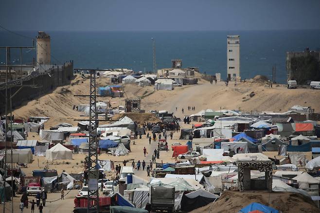 이스라엘과 팔레스타인 무장단체 하마스 간 갈등이 계속되고 있는 가운데 지난 28일(현지시간) 이집트와의 국경을 접한 가자지구 남부 라파에서 사람들이 난민 수용소를 지나치고 있다. [AFP]